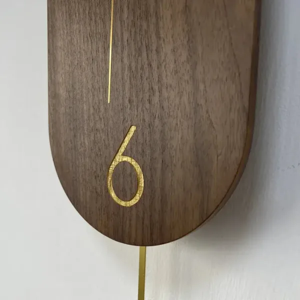 Slingerklok van notenhout met goud